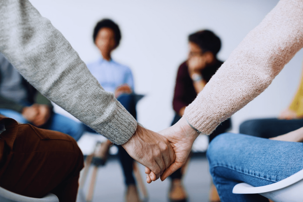 Two individuals holding hands during a support group session, showing solidarity and connection as part of Danville Kentucky Drug and Alcohol Rehab Resources.