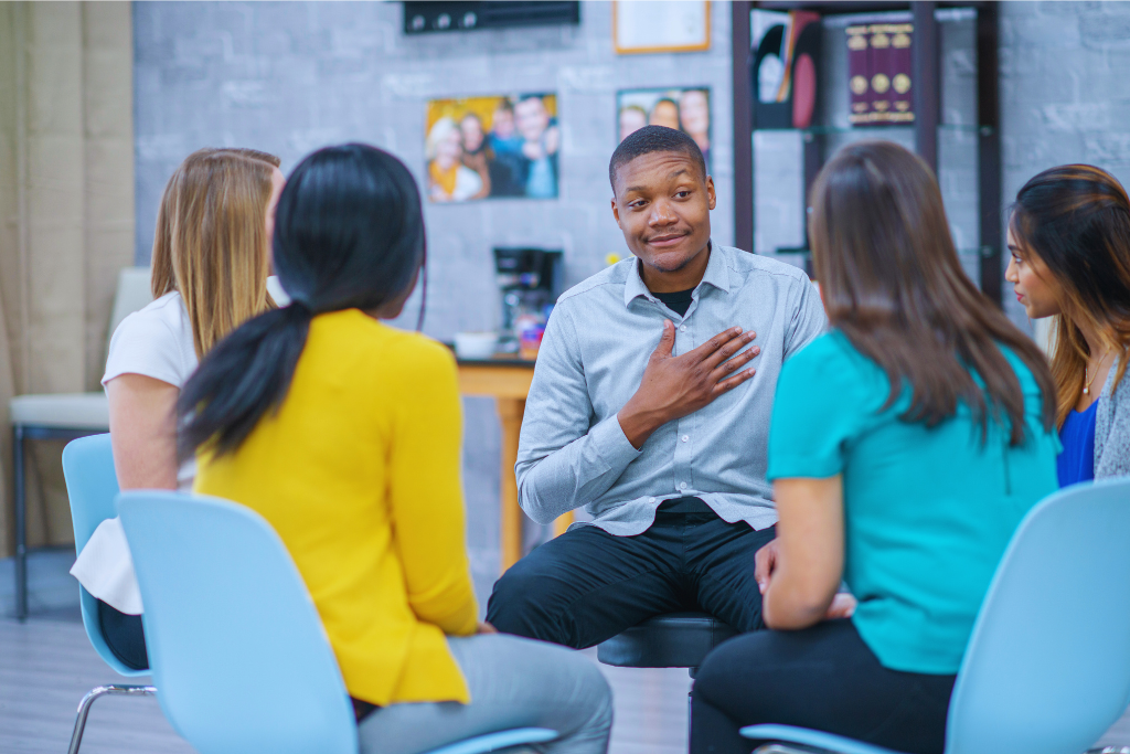 A group therapy session in Morehead, Kentucky Drug and Alcohol Rehab Resources: A man shares his story during a group discussion in a bright, well-lit room, emphasizing openness and healing.