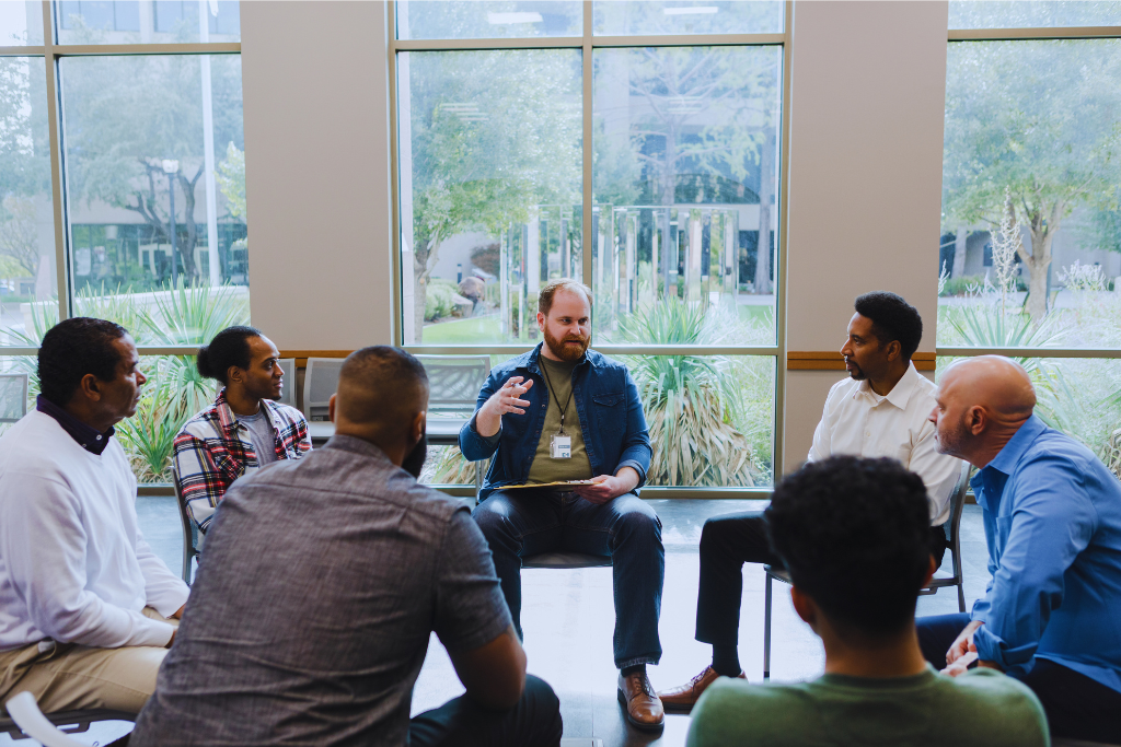A supportive therapy session in Morehead, Kentucky Drug and Alcohol Rehab Resources: A group of individuals sitting in a circle, actively engaged in conversation, receiving guidance and support from a counselor.