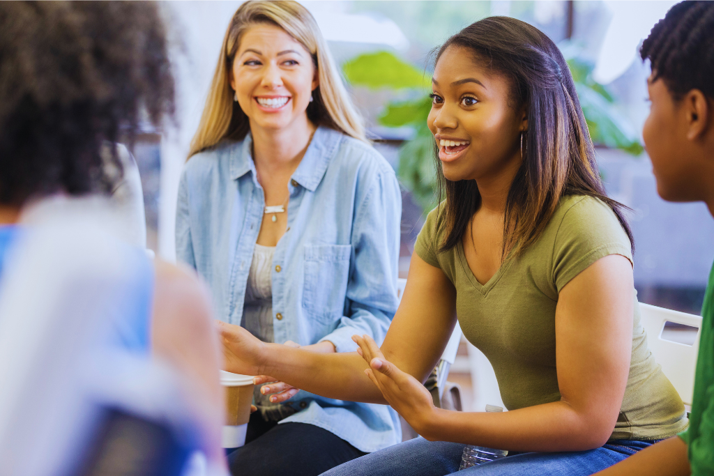 A group of individuals in a therapy session discussing recovery at a Lancaster, Kentucky Drug and Alcohol Rehab Resources. A young woman is actively sharing her story, while others listen attentively, highlighting support and engagement.