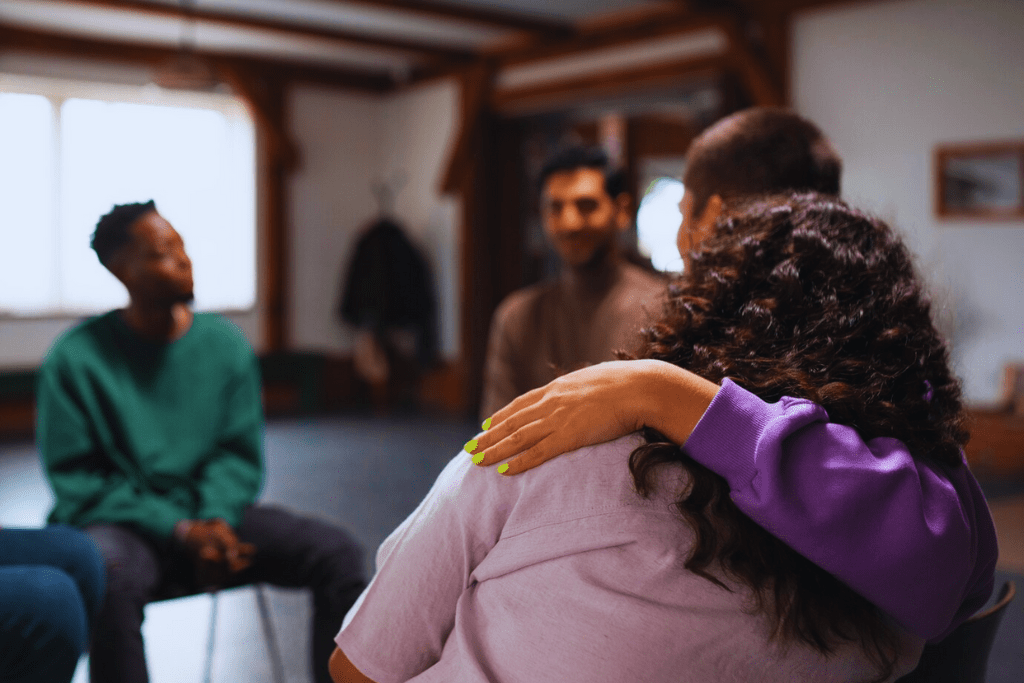 Two participants embracing in a group session, offering emotional support as part of Lawrenceburg Kentucky Drug and Alcohol Rehab Resources.
