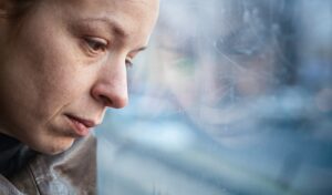 woman with major depression looks out of a window feeling overwhelmed