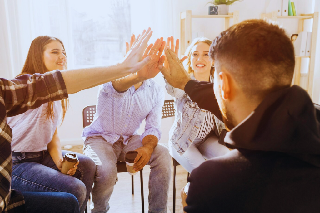 Participants in a recovery group giving a high-five, showing support and celebration as part of Lawrenceburg Kentucky Drug and Alcohol Rehab Resources.